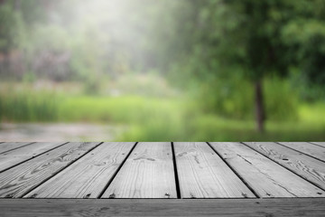 Blurred abstract green bokeh of garden and wooden table background.