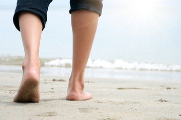 female tourists legs. She walks on the beach of the sea. In the morning