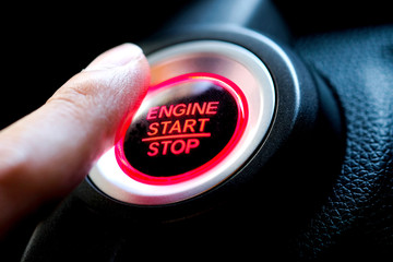 The driver's hand is pressing the car start button. Concept of transportation and technology
