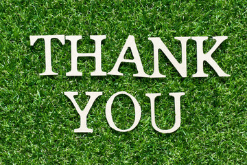 Wood alphabet letter in word thank you on artificial green grass background