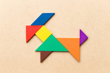 Color tangram puzzle in goat shape on wood background