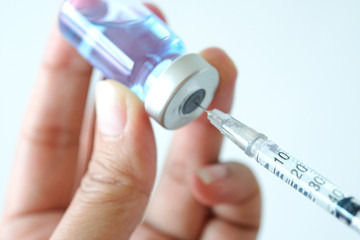 doctor's hand holds a syringe and a blue vaccine bottle at the hospital. Health and medical concepts