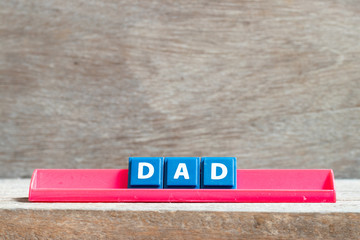 Tile letter on red rack in word dad on wood background