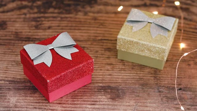hand placing festive golden fairy lights around Christmas gift boxes
