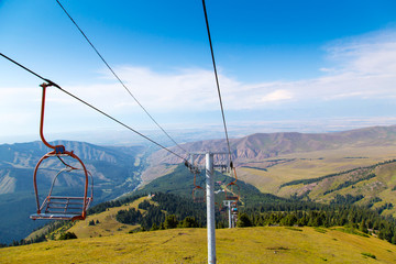 Summer mountain landscape high in the mountains. Tall trees of Christmas trees, ski lift at the ski base.