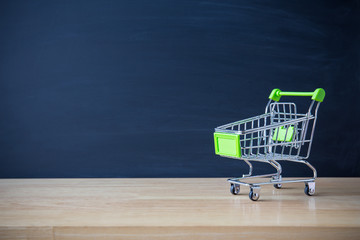 Shopping cart on wood table with black board backdrop. E-commerce and global network online business. copy space for art work design or add text message. Online shopping concept.  © pattanawit