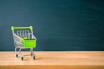 Shopping cart on wood table with black board backdrop. E-commerce and global network online business. copy space for art work design or add text message. Online shopping concept.  © pattanawit