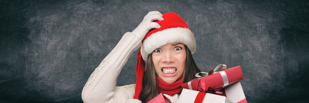 Christmas Stress Holiday Shopping Woman In Santa Hat Stressed Funny Expression On Black Blackboard Banner Panorama. Anxious Lady Shopper Late For Christmas Gifts Stressing About The Budget Spending.