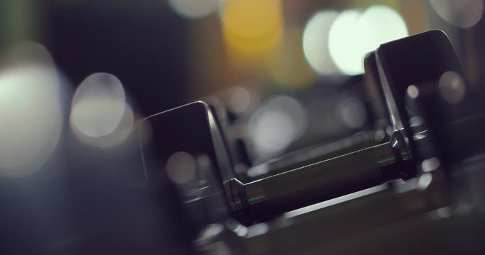 Row of dumbbell in the gym, take a dumbbell with hand. Close-up.