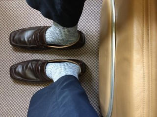 Overhead shot of a person's feet wearing white socks and brown moccasins
