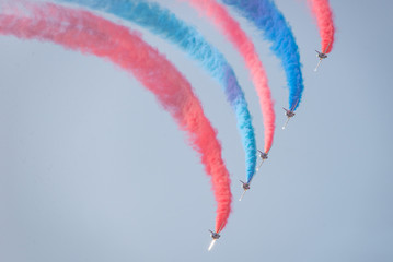 Jets fly, leaving an arc of red and blue smoke