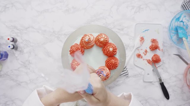 Step by step. Piping buttercream rosettes on top of round three-layer vanilla cake.