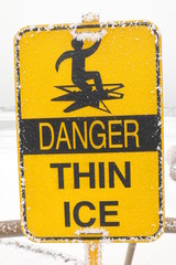 Danger Thin Ice yellow sign of warning people careful this area and have hoarfrost stick on it, in...