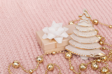 Decorative christmas tree, gift box and gold garland on pink knitted background. New Year or Christmas concept. Template for design, greeting card, invitation