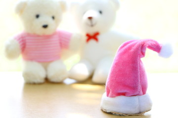 Close up pink Christmas cap on blur couple teddy bear background