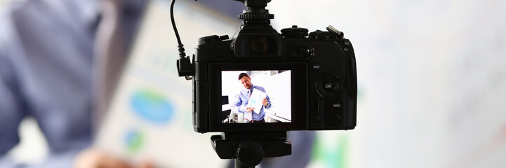 Male in suit and tie show stats graph pad making promo videoblog or photo session in office...