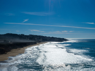 Beach view of heavy waves and clear skies with surfers