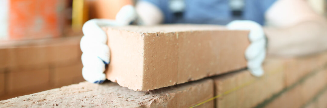 Male smiling builder puts make brickwork repair closeup. Sale of building materials concept.