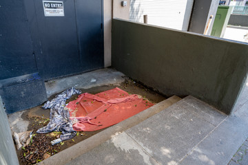 Filth, discarded trash, blankets and towels outside of door labeled no entry
