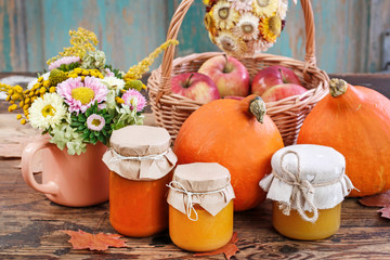 Glass jars with pumpkin jam and honey. Fresh vegetables on the table.