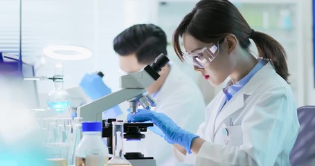 Asian scientist use microscope - Powered by Adobe