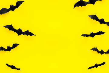Bats cutout on Halloween frame on yellow table top view copy space