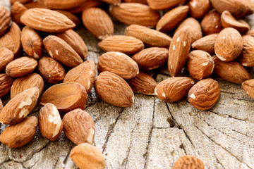 Almonds on rough wooden background, raw fruits.