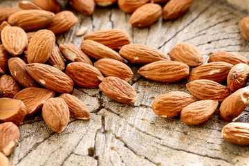 Almonds on rough wooden background, raw fruits.