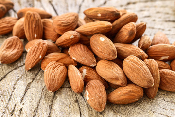 Almonds on rough wooden background, raw fruits.