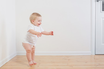 funny little  baby takes first steps on wooden floor