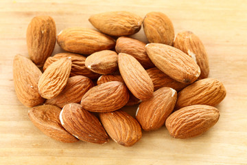 Almonds on rough wooden background, raw fruits.