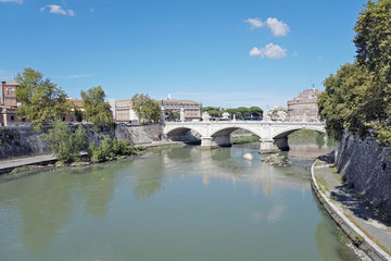 Fototapeta na wymiar View to the Tiber river embankment and the bridge of Victor Emmanuel the Second and the Saint Angel Castle in a distance in the Rome city in Italy