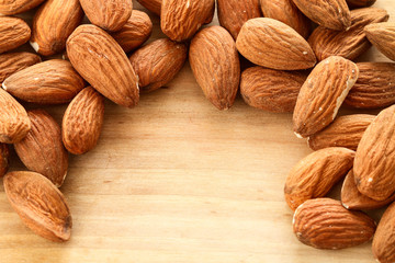 Almonds on rough wooden background, raw fruits.