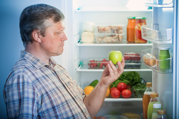 Fototapeta premium mature men at fridge with green apple