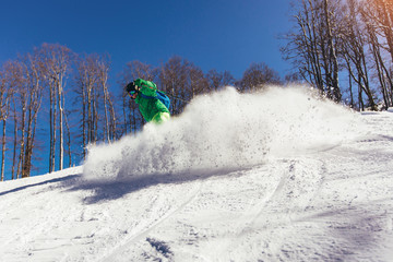 Skier skiing downhill during sunny day in high mountains