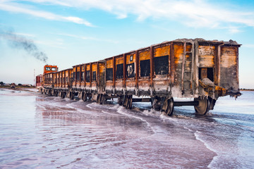 Awesome train rides on rail in the water with white salt on the background of beautiful blue sky.