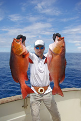 deep sea fishing, man holding two red snapper. Boat fishing, big game