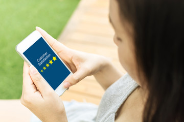 Customer satisfaction review business concept. Woman hand using smartphone with satisfaction rating online mobile application