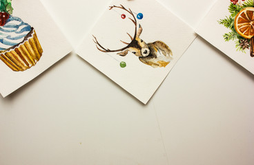 Christmas cards are suspended by clothespins on white wall . Watercolor holly set.