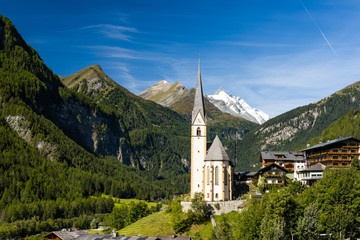 Pitcuresqe Church in Austria Village. High Alps Mountains in Background