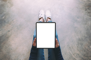 Top view mockup image of a woman holding black tablet pc with blank white screen while sitting on the floor