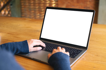 Mockup image of a woman using and typing on laptop computer keyboard with blank white desktop screen on wooden table