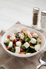Homemade Shepards salad in a white bowl with cucumbers, parsley and feta, side view. Copy space.