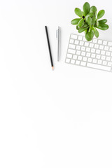 Elegant business workspace with keyboard, pen and small flower. Office desktop concept. Top view