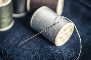 Needle and spool of thread on jeans fabric