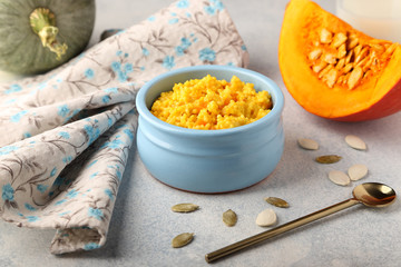 Morning breakfast, healthy and tasty millet porridge with pumpkin, in a blue plate on a blue background.