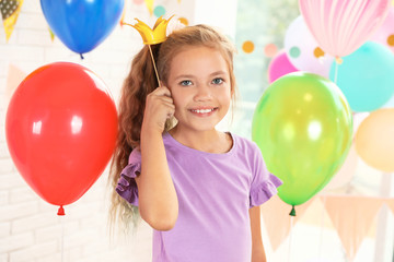 Happy girl near bright balloons at birthday party indoors