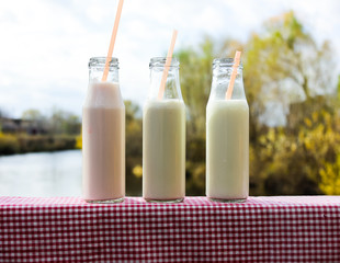 ice milkshake or milk cocktail  in tree glass botls on wooden table outdoors
