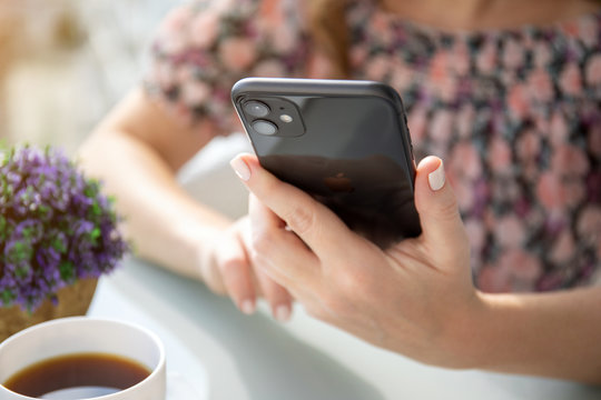 Woman hand holding Apple iPhone 11 and sitting at table