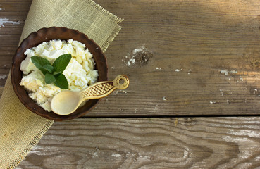  Cottage Cheese in a ceramic bowl on the kitchen table. Dairy products for the healthy breakfast. Homemade natural cottage cheese prepared from organic dairy products. Healthy food concept. Soft focus